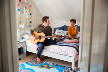 Wall Mural - Single Father Playing Guitar With Son Who Drums On Cushion In Bedroom