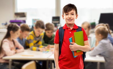 Wall Mural - education and people concept - smiling little student boy in red polo t-shirt in glasses with books and bag over school class background