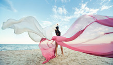 Slim Woman At The Beach With Long Pink Fabric. Sky Background At The Summer. Classic Dancer On The Nature