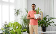 © Syda Productions - people, nature and plants concept - indian man holding flower in pot taking care of houseplants at home