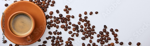 top-view-of-coffee-in-brown-cup-on-saucer-near-scattered-roasted-beans-panoramic-shot