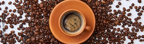 panoramic-shot-of-delicious-coffee-in-brown-cup-near-scattered-roasted-beans-on-white-background