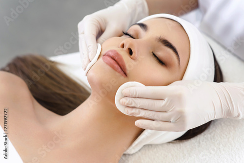 close-up-of-hands-of-skillful-beautician-cleaning-and-touching-female-face-with-cotton-pad-or-sponge-the-woman-is-lying-and-relaxing-her-eyes-are-closed-with-pleasure