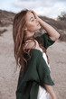 © Iveta - young caucasian woman in white dress and green knitted cardiagan stay on the beach