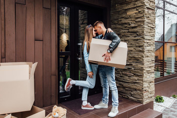 Happy couple  looking each other with cardboard boxes in new house at moving day.