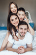 © Тарас Нагирняк - Photo of young family of four lying on nice white bed. Family weekend.. Resting and relax..