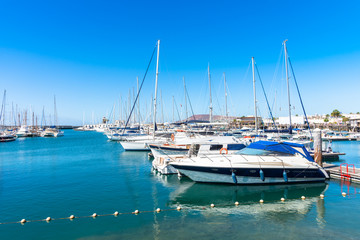 Wall Mural - Unique skyline view Marina Rubicon Playa Blanca coastal vacation resort, famous yachting port and market place, with volcanic mountains in the background. Lanzarote, Canary Islands, Spain.