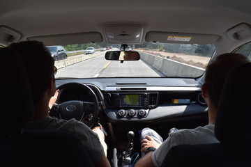 View from inside of the car two people inside while driving on the highway on a summer day