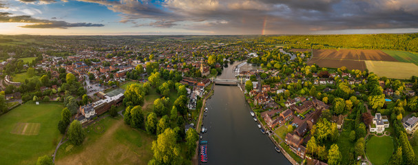 Dramatic aerial panoramic view of the beautiful town of Marlow in Buckinghamshire UK, captured after a rain storm, with a rainbow on the horizon