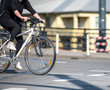 © vit - Young stylish woman cyclist in black clothes crosses the road by bike while driving through pedestrian crossing at a crossroad