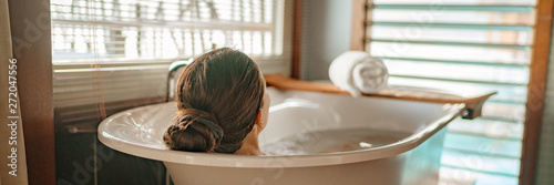 Fotomural Luxury bath woman relaxing in hot bathtub in hotel resort suite room enjoying pampering spa moment lifestyle banner panorama