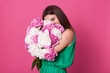 © sementsova321 - Portrait of sweet attractive female holding huge bouquet of peonies close to her, covering most part of her face with it, looking at camera, enjoying getting floral gifts, wearing green summer dress.