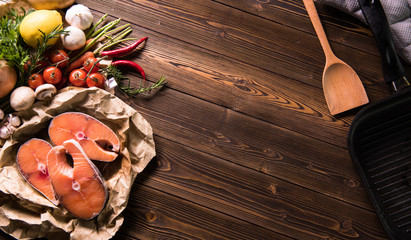 Wall Mural - Fresh raw salmon fish steak with herbs and vegetables on wooden background