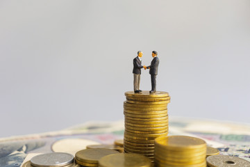 Leader businessman suits handshake stand among on stack of coin and money. Financial banner concept.