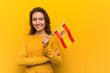 © Asier - Young european woman holding a spanish flag smiling confident with crossed arms.