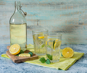 2 Glasses and bottle of fresh lemon juice with mint leaves