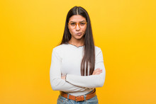 Young Pretty Arab Woman Against A Yellow Background Frowning Face In Displeasure, Keeps Arms Folded.