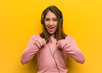 Young cute woman listening to music surprised, feels successful and prosperous