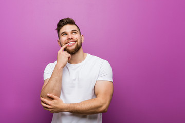 Young handsome caucasian man relaxed thinking about something looking at a copy space.