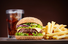 Cheeseburger With French Fries And Glass Of Cola On Wooden Table