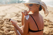 © verona_studio - Beauty Woman applying sunscreen creme on tanned shoulder. Skincare. Body Sun protection suncream. Bikini hat woman applying moisturizing sunscreen lotion on back.