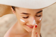 Suntan Lotion Woman Applying Sunscreen Solar Cream. Beautiful Happy Cute Woman  Applying Suntan Cream To Her Nose.