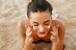 © verona_studio - Suntan lotion woman applying sunscreen solar cream. Beautiful happy cute woman  applying suntan cream from a plastic container to her nose with ocean in background.