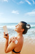 © verona_studio - Woman applying sunscreen creme on  tanned  shoulder. Skincare. Body Sun protection suncream. Bikini hat woman applying moisturizing Suntan lotion on back.