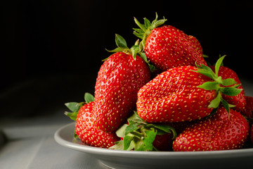 Wall Mural - A pile of strawberries in a gray plate on a gray wooden table on a black background