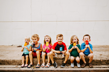 group of kids eating frozen colorful popsicles in the summer