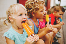 Group Of Kids Eating Frozen Colorful Popsicles In The Summer