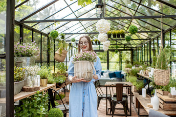 Portrait of a young woman standing with lavender at the entrance of the beautiful greenhouse or flower shop