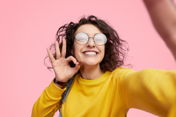 Wall Mural - hipster showing approving gesture and taking selfie