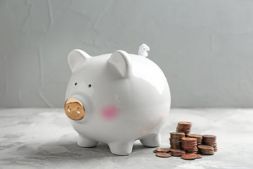 Wall Mural - Piggy bank and coins on table against grey background