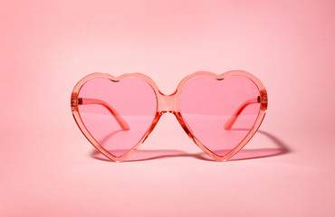 Stylish heart shaped glasses on color background