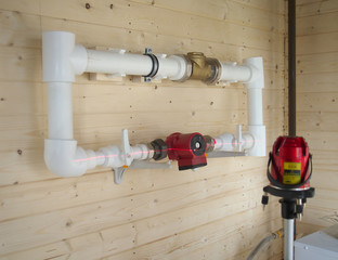 mounting of gravity heating system equipment with laser level in a boiler room. Circulation pump, stopcock, return valve, polypropylene tube and laser level