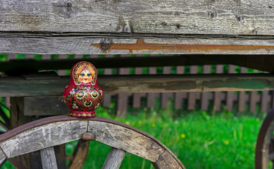 Wall Mural - Nested doll on the background of an old wooden cart. Matryoshka is a national Russian souvenir.