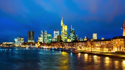 Canvas Print - Frankfurt am Main, Germany. Skyline of Frankfurt, Germany in the sunset with famous illuminated skyscrapers and river. Time-lapse of cloudy sky at night, zoom in