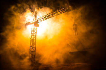 Abstract Industrial background with construction crane silhouette over amazing sunset sky. Tower crane against the evening sky. Industrial skyline