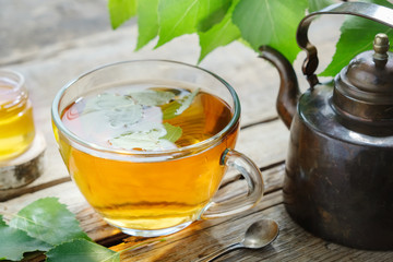 Wall Mural - Birch leaves, healthy herbal tea cup, honey jar and vintage copper tea kettle.