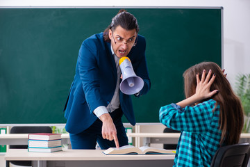 Wall Mural - Young handsome teacher and female student in the classroom 