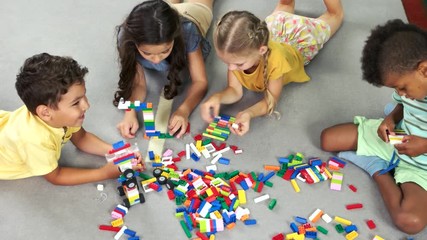 Wall Mural - Kids laying on the floor and playing with toys. Children playing constructor toys. View from above.