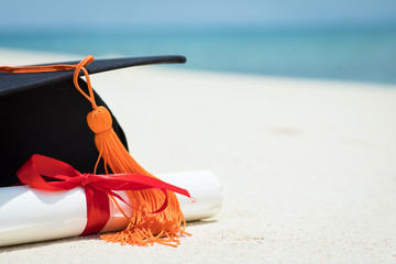 Close up Graduation cap and certificated on the beach with beautiful sea in summer,Education in summer Concept