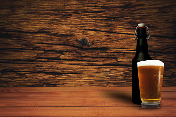 Poster - Glass of beer on a old oak table of wood. Beautiful brown wooden background.