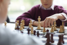 Girl In Purple Sweater Playing Chess, Making Move And Putting Indecisively Chess Piece On Board