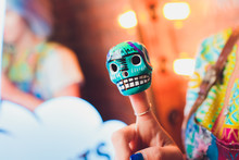 Small Mexican Skulls On A Female Finger On A Colored Background.