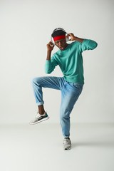 Wall Mural - Happy Afro American man with red headband dancing on white background