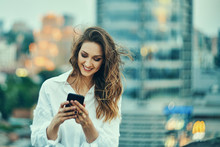 Young Woman Over Cityscape Holding A Smart Phone Texting