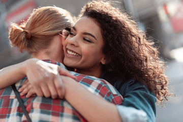 Joyful young woman is hugging guy outside