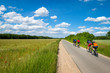kleine Gruppe Radfahrer trainiert in schöner Landschaft auf einer Landstraße im Sommer. Am Wegesrand blühen bunte Blumen
